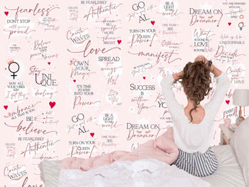 Woman does her hair while sitting on bed in front of pink bedroom wallpaper